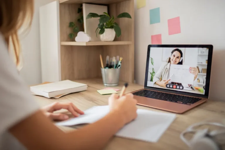 Pessoa em casa fazendo anotações durante uma sessão de terapia por videochamada no notebook