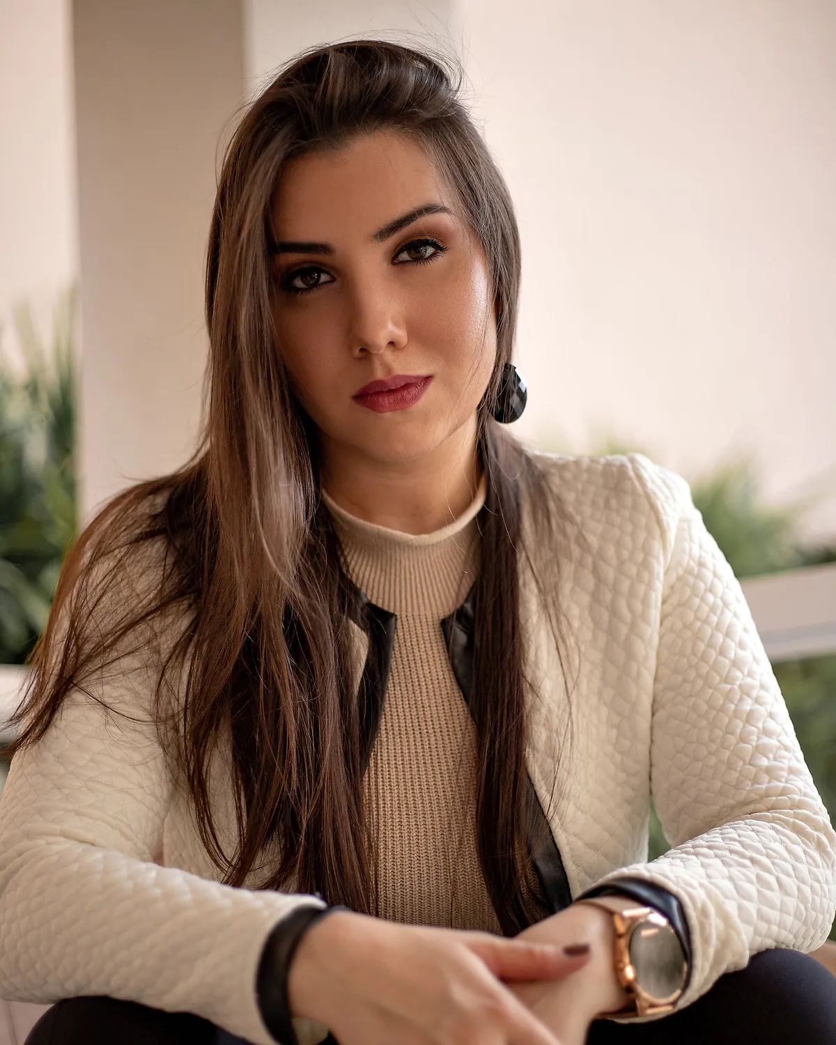 Psicóloga Jéssica Barbosa (CRP 04/60880) sentada, com casaco claro, em retrato para o atendimento de terapia online